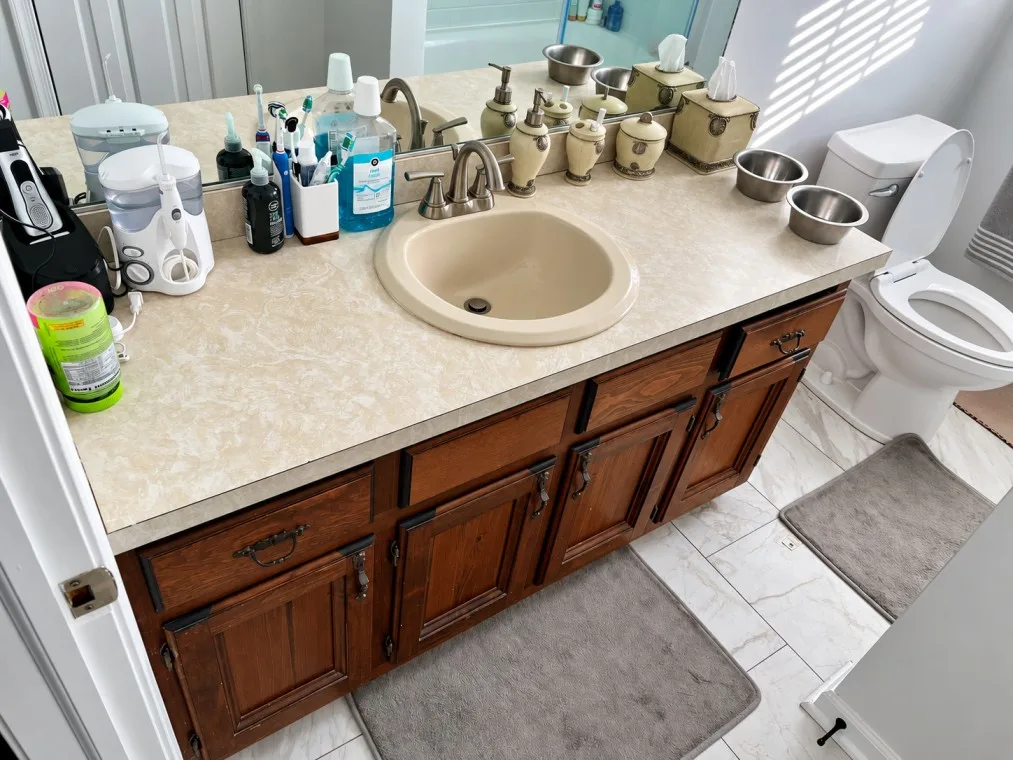 Before bathroom vanity with outdated countertop and wooden cabinets