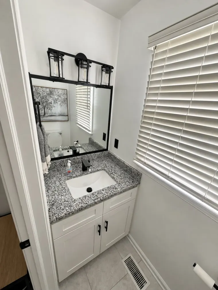 Modern powder bathroom with granite vanity countertop and black fixtures