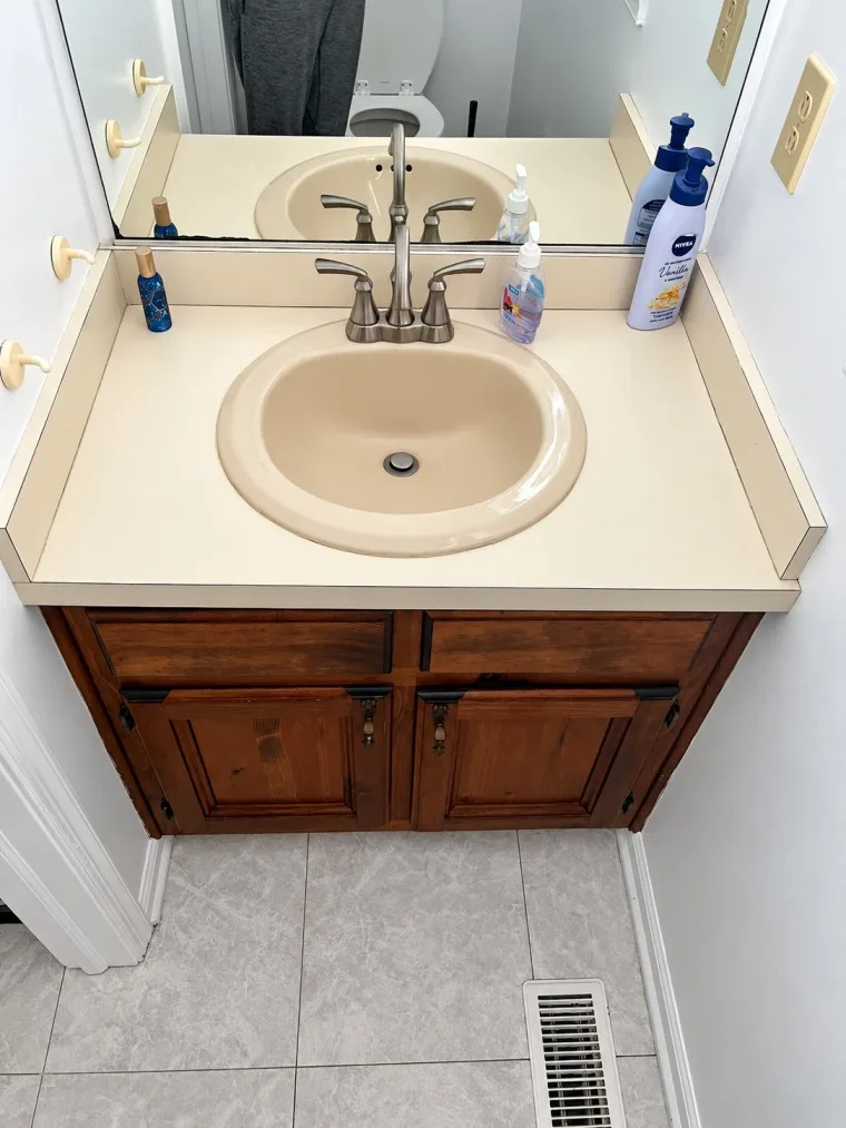 Before bathroom vanity with outdated countertop and wooden cabinets